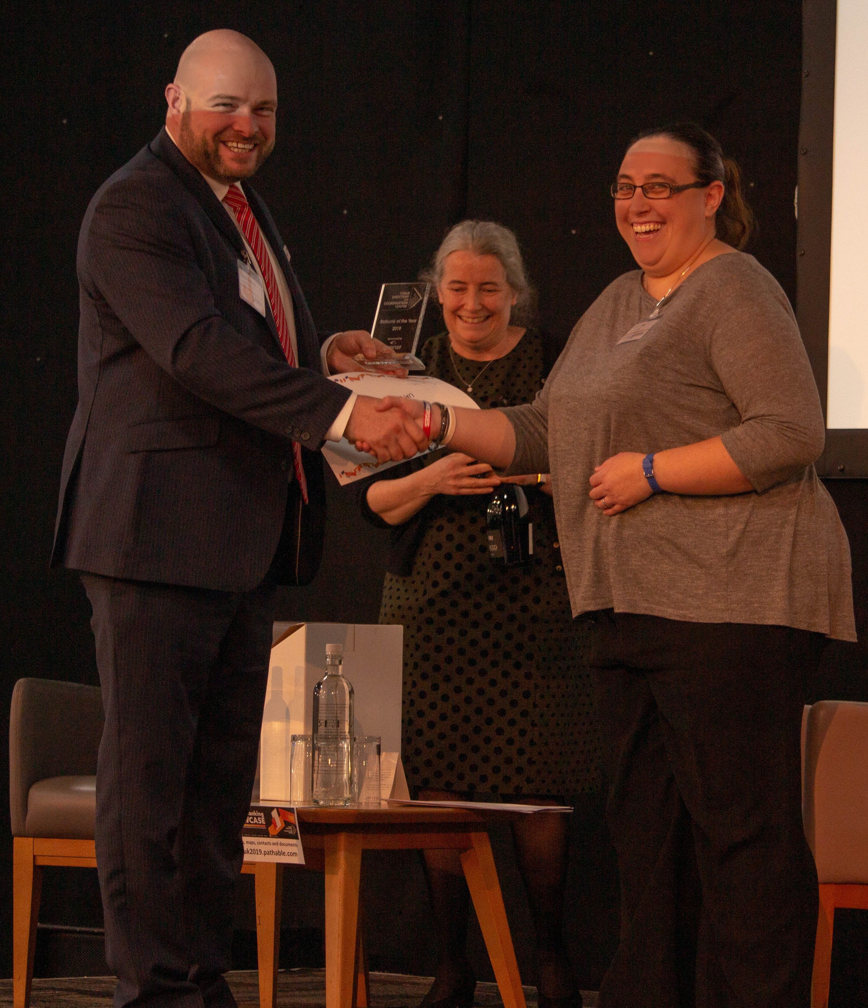 UK MND Collections winning UK Biobank of the Year 2019 James Siddorns from Greiner Bio-One, award sponsor, congratulating Kirsten Kelly. Amanda Gibbon, Chair of the steering committee, looks on after announcing the winner.